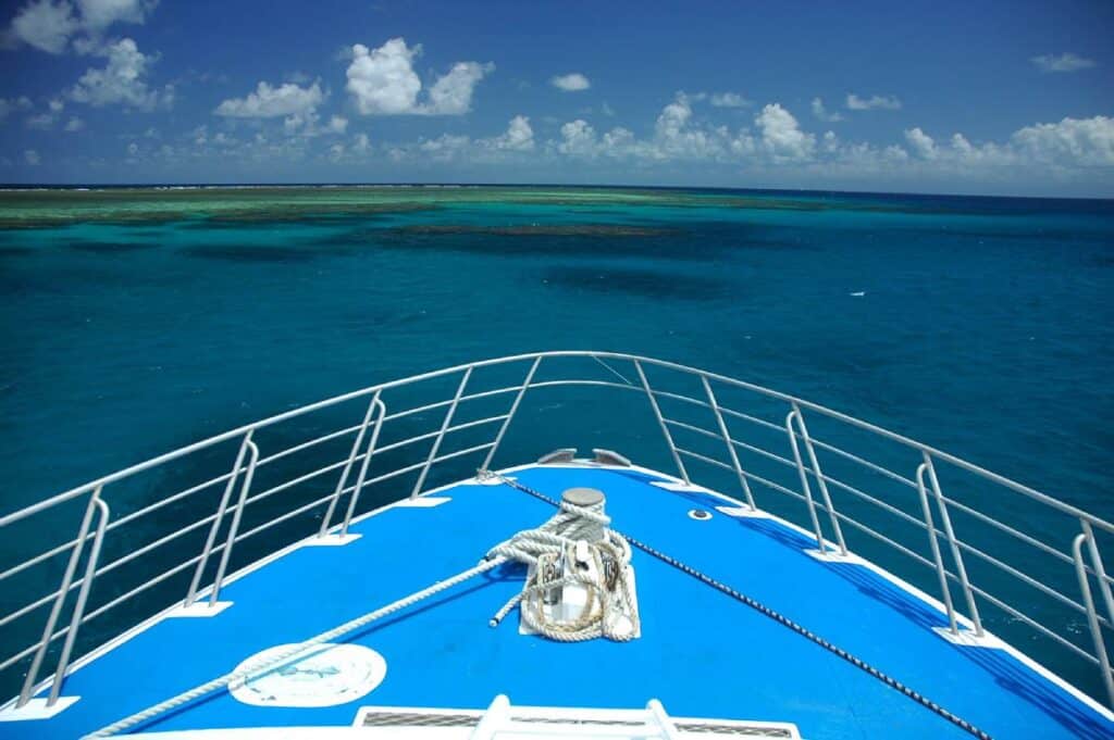 View from the bow of a cruise boat heading towards the vibrant and clear turquoise waters of the Great Barrier Reef, a must-visit destination for anyone travelling to Port Douglas.