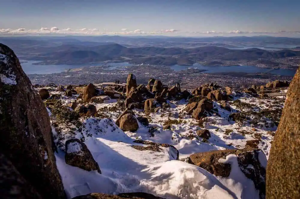 A panoramic view of Hobart from snow-capped Mount Wellington, showcasing the city amidst a winter wonderland, highlighting the occurrence of snow in Hobart.