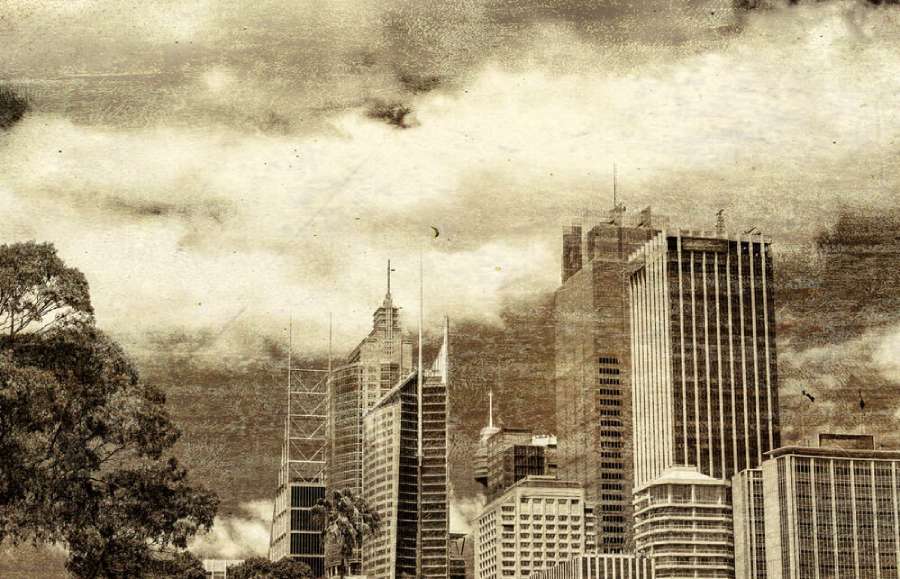 Vintage sepia-toned image of the Sydney skyline, with modern skyscrapers rising amidst cloudy skies, conveying a sense of the old and new. This image evokes the timeless stories that are a part of Sydney ghost tours.