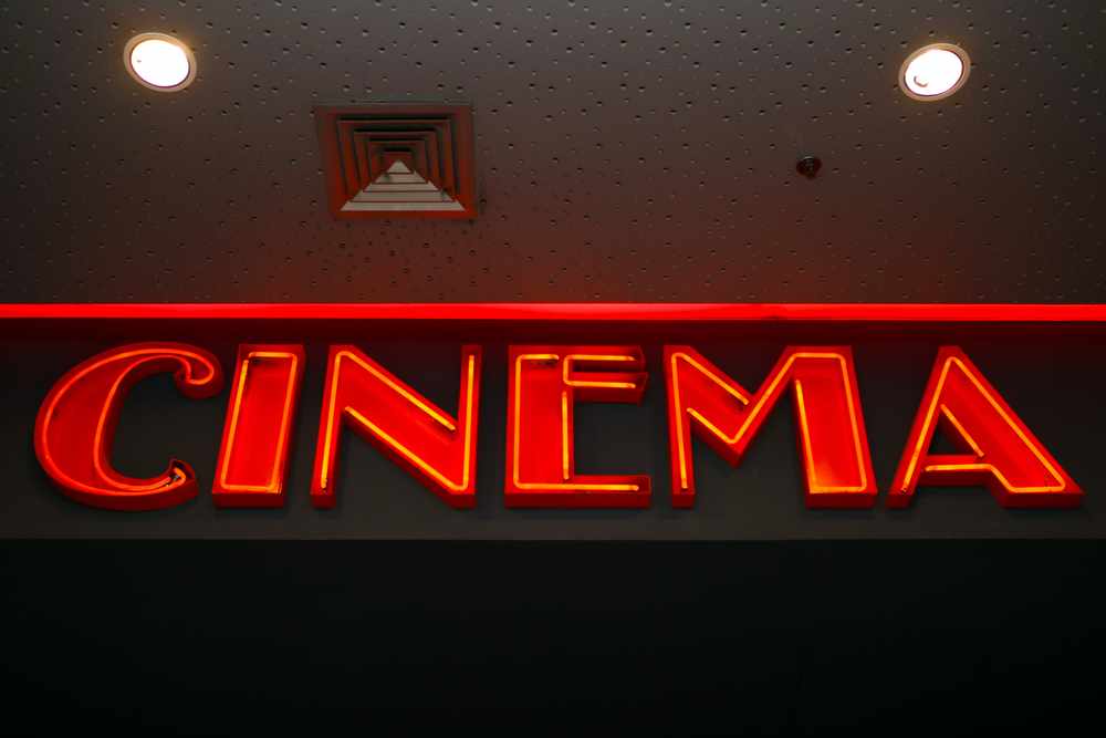 Neon sign of a cinema in a warm, inviting red glow, a cosy indoor activity for those looking for entertainment options and things to do in Hobart in winter.