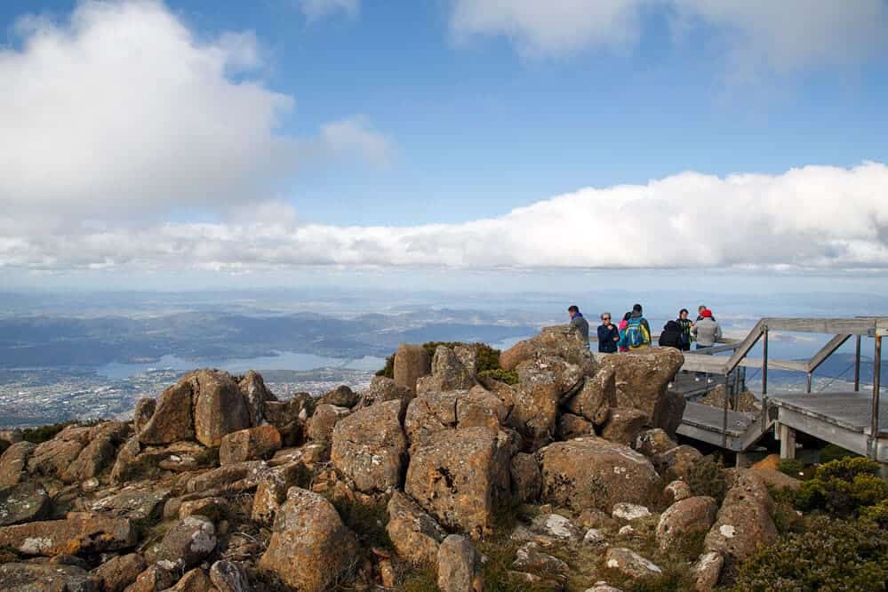 Group of travellers at the summit of Mount Wellington, a popular destination on Hobart half-day tours, enjoying panoramic views of Hobart and its surrounding waters, illustrating the memorable experiences accessible just a short journey from the city.