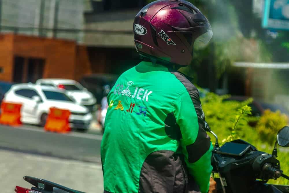 A Gojek driver waiting on a scooter in Bali, offering a local and convenient ride-hailing alternative to Uber for navigating the bustling streets.