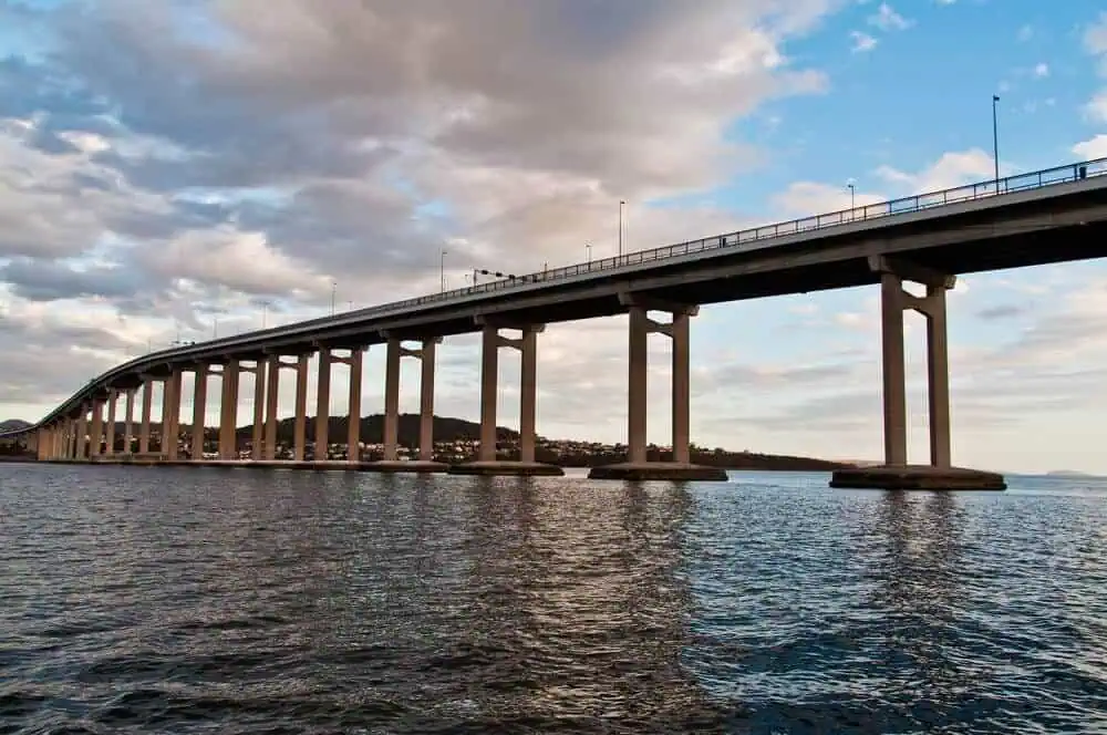 View of the Tasman Bridge in Hobart, a highlight of Hobart half-day tours, as it stretches across the Derwent River against a backdrop of a dusky sky, symbolising the connection between city life and natural beauty.