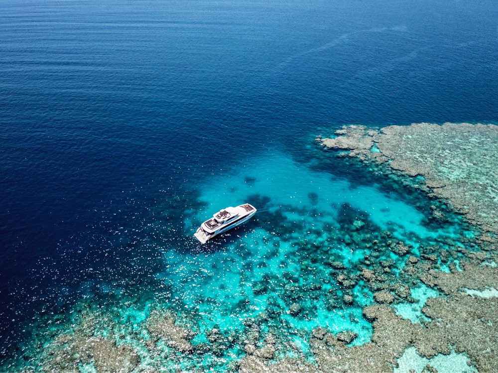 Luxury boat anchored near the vibrant coral reefs of the Great Barrier Reef, a popular destination for those who travel to Port Douglas to experience world-class diving and snorkeling.