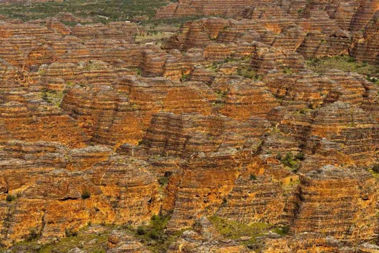 Aerial view of the beehive-shaped domes in the Bungle Bungles at Purnululu National Park, Western Australia, showcasing the striking orange and black sandstone layers. This iconic landscape captures the raw beauty of the Kimberley and highlights one of the must-do outback experiences for any Australian adventure.