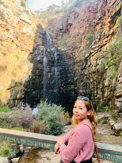 Kate standing near the base of First Falls in Morialta Conservation Park, surrounded by rugged cliffs, showcasing the beauty of Australian waterfalls and the serene atmosphere of this natural site.