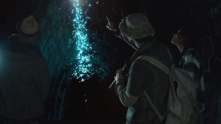 A group of people inside a cave mesmerized by the glowing blue light of glow worms, highlighting the enchanting experiences available with a Byron Bay travel deal.