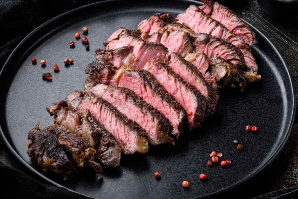 Juicy grilled rib-eye beef steak served rare, presented as part of affordable Christmas lunch in Melbourne, highlighting delicious yet budget-friendly dining options available for the holiday season.
