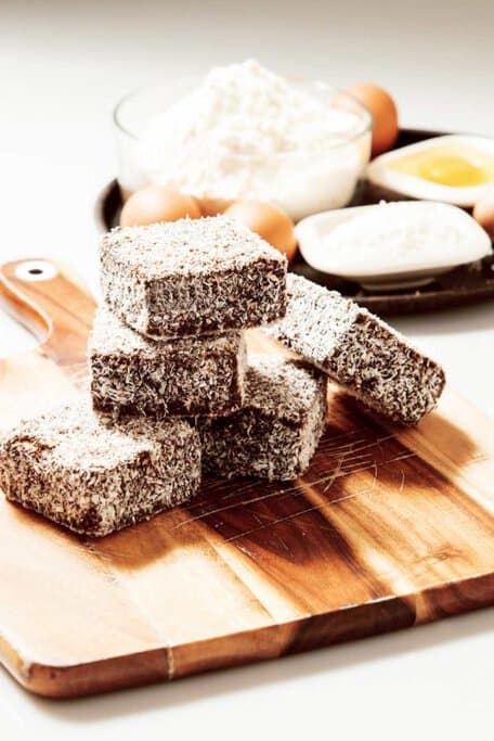 A stack of lamingtons coated in chocolate and coconut, a beloved treat often featured in Australia's Christmas food celebrations.