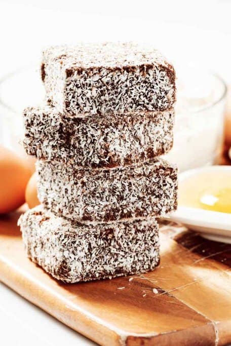 A stack of freshly made lamingtons, a beloved Australian sweet treat, coated in chocolate and desiccated coconut. These classic sponge cakes are an essential part of Aussie culinary culture and remain one of Australia's most iconic desserts.