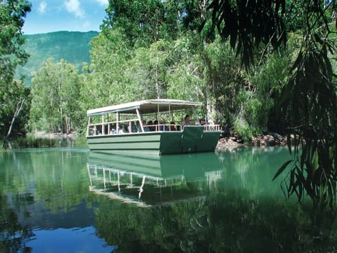 Tourists enjoying a peaceful boat tour in the lush green surrounds of Hartley's Crocodile Adventures, a popular activity for those visiting on a Port Douglas or Cairns travel itinerary.