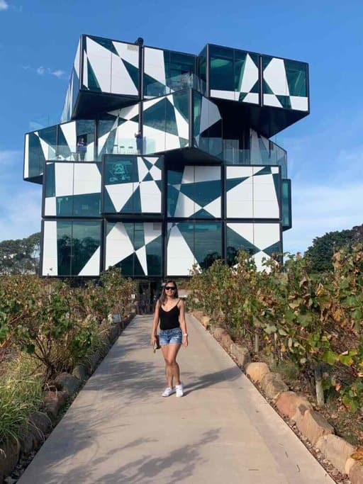 The author, Kate, strolls along the path leading to the d'Arenberg Cube in McLaren Vale, showcasing the unique architecture and vineyard experiences available as a winter activity near Adelaide.