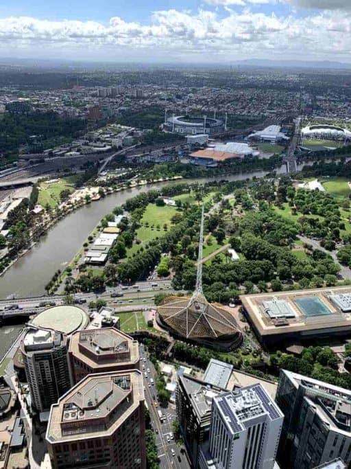 Aerial view of Melbourne, showcasing the Yarra River, Melbourne Cricket Ground (MCG), and Arts Centre Melbourne with its iconic spire. This perspective highlights one of Melbourne's most Instagrammable places, offering a stunning panorama of the city’s landmarks and lush greenery.