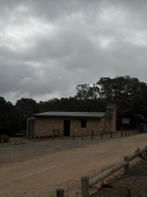 Dennis Hut at Waitpinga Campground, a heritage stone building built in 1890, now sitting near the campground entrance with a BBQ area tucked behind it—highlighting a mix of rustic charm and practical amenities for campers.