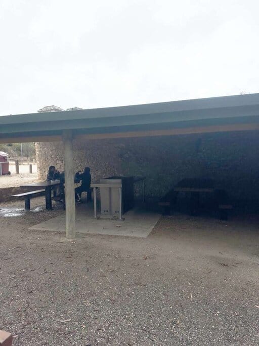 Covered BBQ area behind Dennis Hut at Waitpinga campground, featuring picnic tables and a public grill—offering a sheltered spot for campers to cook and relax after a day exploring the coast.