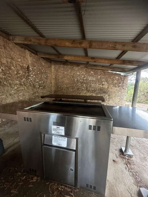 Close-up of the public gas BBQ at Waitpinga campground, set beneath a rustic shelter with stone walls—giving campers a clean and sheltered space to cook meals near the coastal trails of Newland Head Conservation Park.
