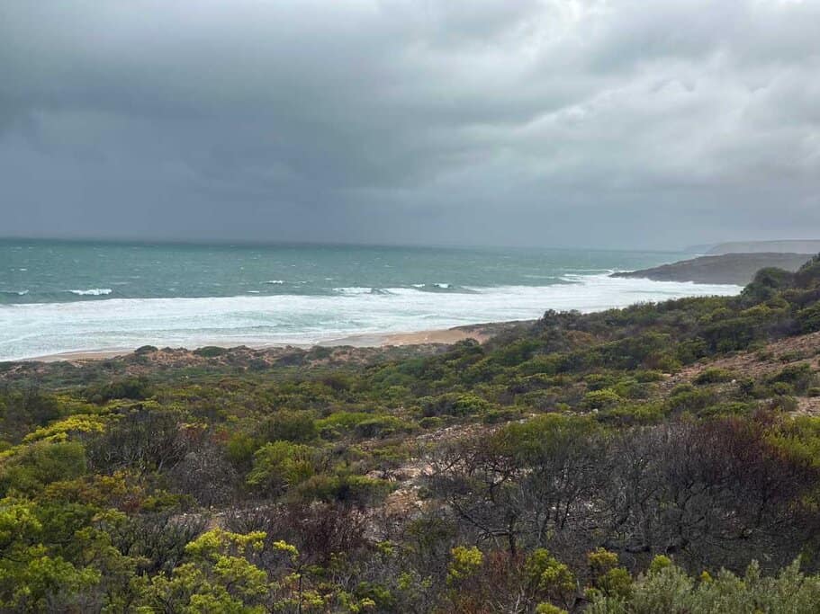 Dramatic coastal view of Waitpinga Beach with wild surf and dark skies, seen from the dunes near Waitpinga Campground—showcasing the raw beauty and rugged seascape campers wake up to on the Fleurieu Peninsula.