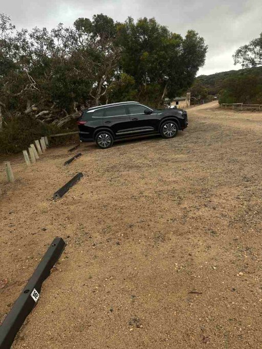 Marked gravel parking bays at Waitpinga Campground with a black SUV parked near the bushland edge—illustrating the designated parking setup mentioned in guides about what you need to know before camping at Waitpinga.