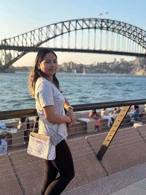 Author standing in front of the iconic Sydney Harbour Bridge, comparing the highlights of Sydney and Brisbane.