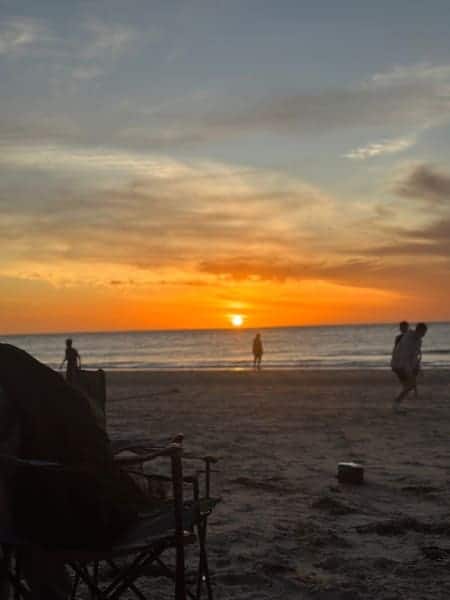 The sun dips below the horizon at Glenelg Beach, Adelaide, painting the sky in vibrant hues of orange and yellow. Couples on a Valentine's Day cruise would witness this stunning sunset, alongside the tranquil sea and the gentle hustle of beachgoers, encapsulating a perfect romantic evening.