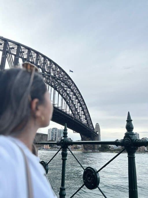 The author Kate gazes towards the Sydney Harbour Bridge, a stunning backdrop that visitors staying at Sydney hotels with rooftop pools could admire while lounging by the poolside