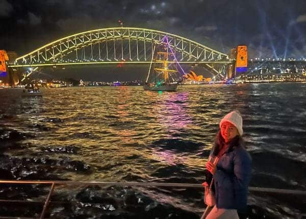 The author, Kate, enjoying a harbour cruise in Sydney at night, with the illuminated Sydney Harbour Bridge creating a romantic setting, perfect for a Valentine's Day in Sydney. 