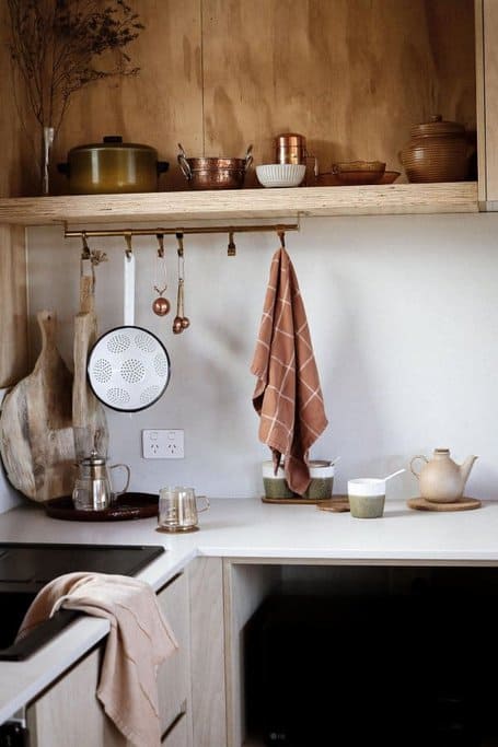 A modern kitchen setup in a luxury cabin showcasing wooden shelves with copper pots and rustic cookware, relating to the post about the best luxury cabin near Derby, which features elegant interior design and cosy amenities for a comfortable stay.