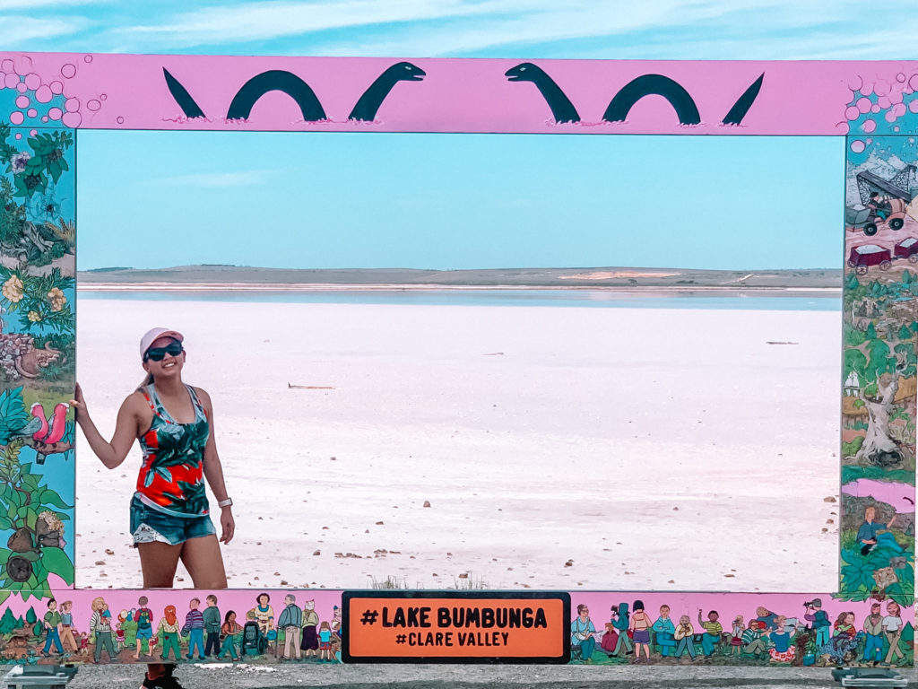 Kate, the author, posing at the vibrant Lake Bumbunga in Clare Valley, with its signature pink hues and interactive art installations, a unique and picturesque destination among the various things to do in Clare Valley."