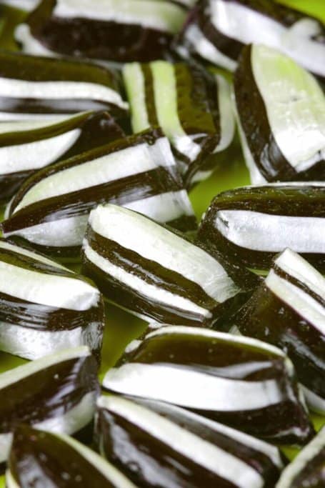 The image shows a close-up of black and white striped candies, likely liquorice-flavoured, commonly referred to as "lollies" in Australia.