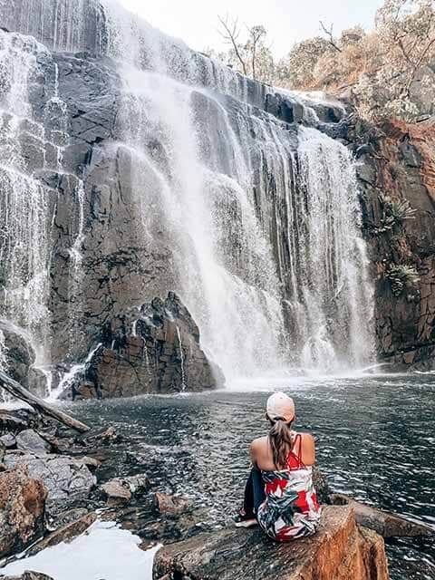 Kate standing in front of the cascading Mackenzie Falls in Grampians National Park, highlighting the adventure of camping in the Grampians.