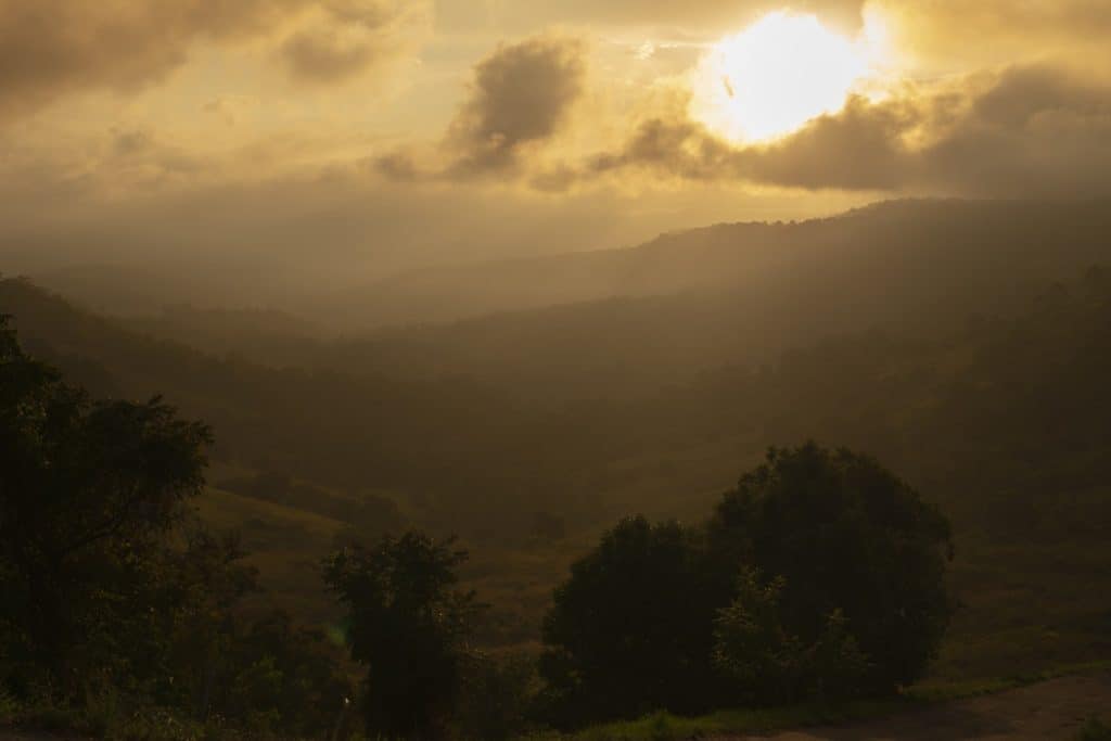 A golden sunset casting a warm glow over the rolling hills and valleys of the Maleny Hinterlands, a picturesque destination along one of Queensland's best scenic drives.