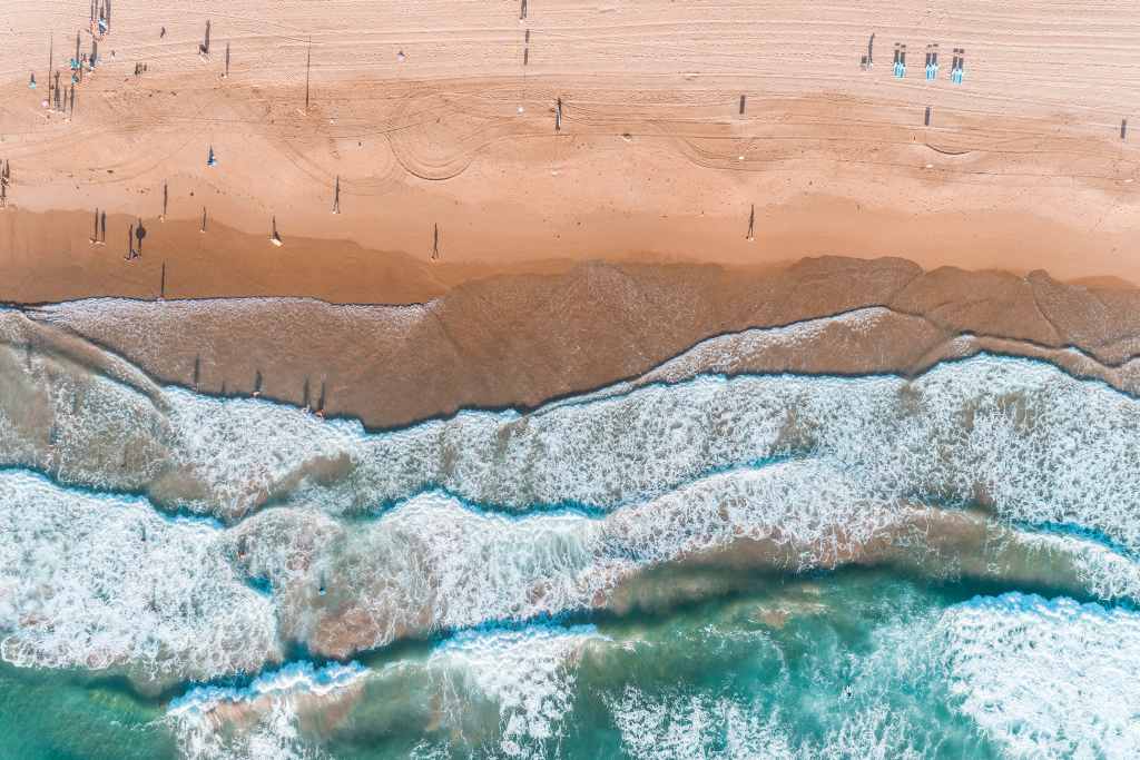 The waves and people in a drone shot at Manly Beach