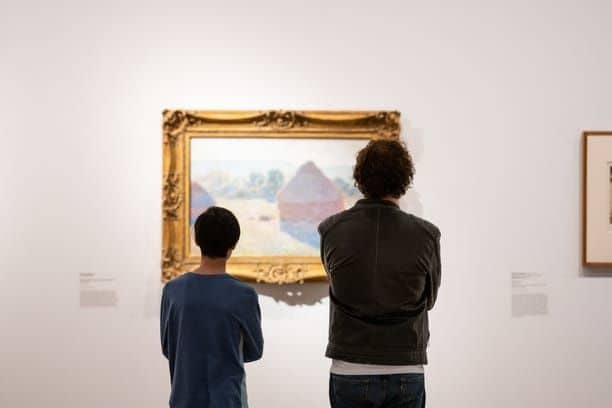 Two people admiring a painting inside the National Gallery of Australia, reflecting the vibrant cultural scene as a pro in the 'Pros and cons of living in Canberra'.