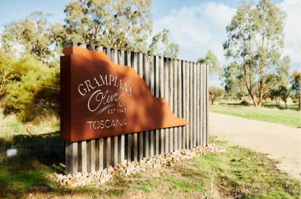 Signboard of Grampians Olive Co Toscana with a rustic wooden fence background, symbolizing the entrance to their estate in the scenic Grampians region, perfect for a post about Australian olive oil producers.