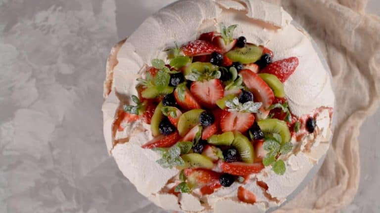 A festive pavlova topped with fresh strawberries, kiwi, and blueberries, a classic Christmas dessert treat perfect for summer celebrations