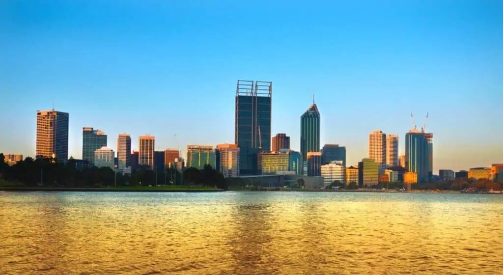 Perth skyline at dusk with buildings reflecting on the water, showcasing the city’s modern architecture. This image relates to the post by highlighting the beauty and appeal of Perth as a travel destination, addressing the question 'is Perth worth visiting' for travellers seeking vibrant cityscapes.