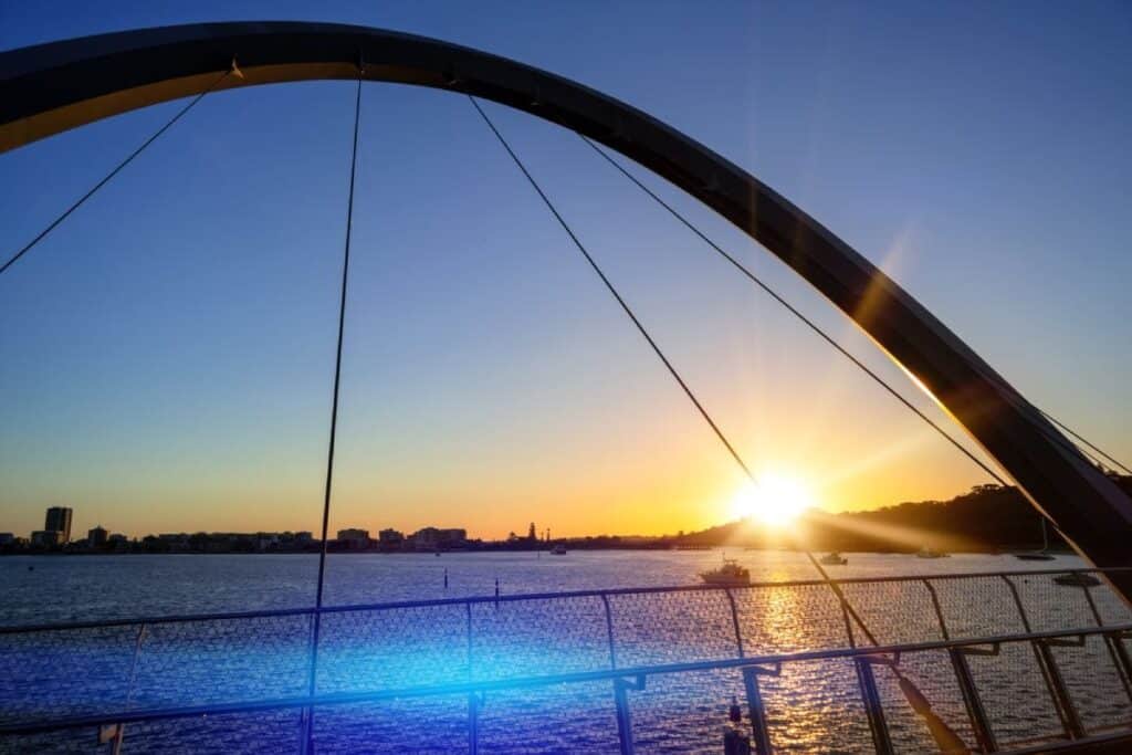 Beautiful sunset view from a bridge in Perth, with the sun setting over the water and city skyline. This image connects to the post by illustrating why Perth is worth visiting, especially for those who enjoy stunning sunsets and scenic waterfront experiences.
