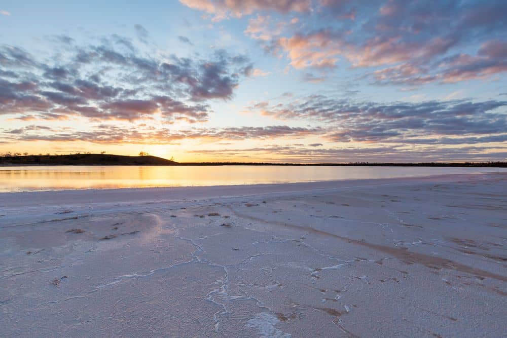 A stunning sunset over Pink Lake in Murray-Sunset National Park, Victoria, Australia, with soft pastel hues reflecting on the salt-crusted shoreline. This remote and otherworldly landscape is one of Victoria’s most unique natural wonders, known for its striking pink-hued salt lakes and vast outback scenery.