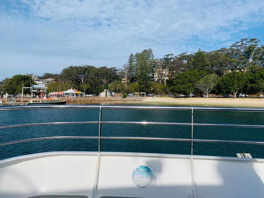 The view from a dolphin-watching tour boat approaching the vibrant shoreline of Port Stephens, highlighting a starting point for exploring the best times for dolphin watching in the area.