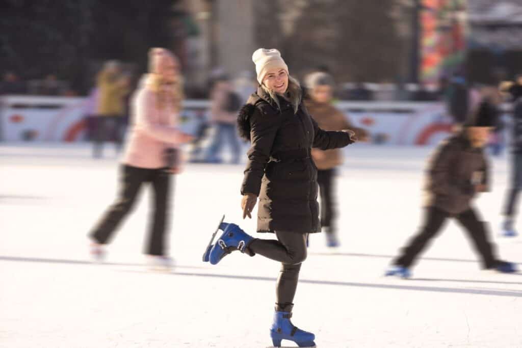 A woman ice skating joyfully at an outdoor rink, surrounded by other skaters. Ice skating during the holiday season is one of the festive things to do in Melbourne, offering a fun winter activity in the heart of the city’s Christmas celebrations.