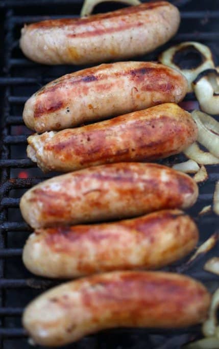 A row of sizzling sausages grilling over an open flame with caramelised onions, a staple of the classic Aussie barbecue. This simple yet iconic Australian food is a favourite at backyard gatherings and community sausage sizzles.