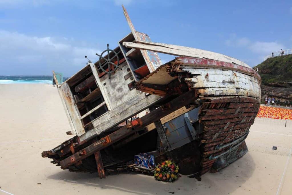 A weathered boat sculpture displayed on Bondi Beach as part of the Sculpture by the Sea exhibition, showcasing the artistic attractions highlighted in a Bondi Beach travel guide for unique experiences.