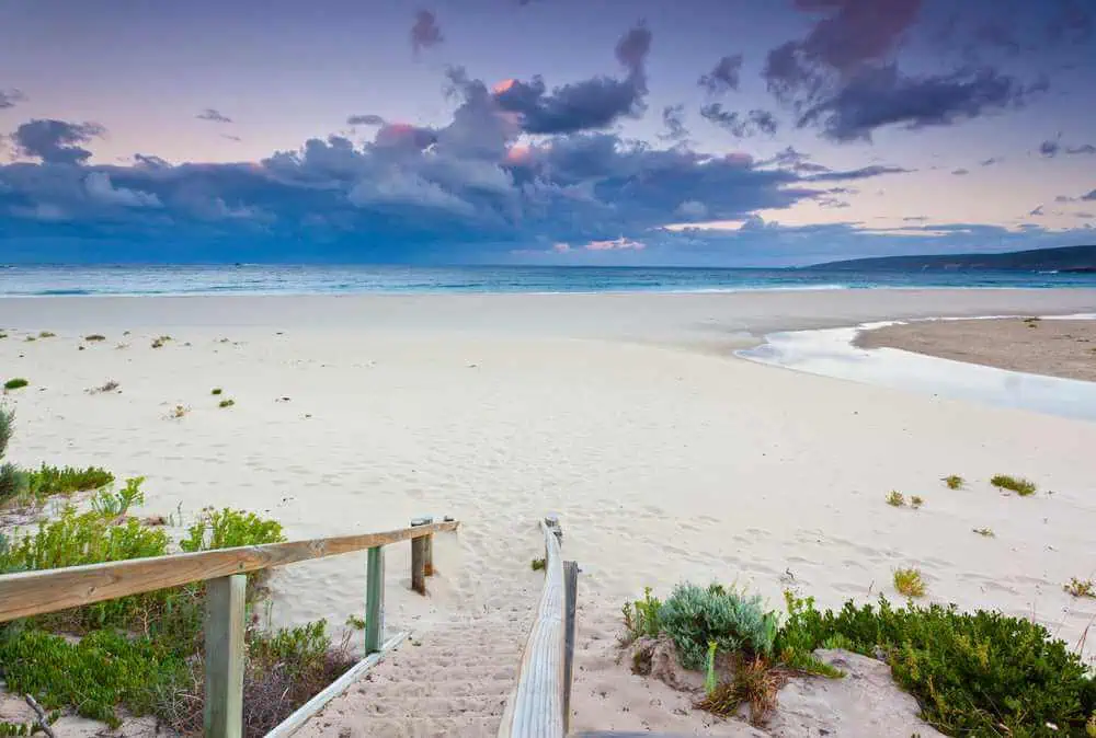 Dusk falls on Smiths Beach as a dramatic sky looms over the quiet, expansive sands and tranquil waters, capturing the peaceful essence of Western Australia's coastlines.
