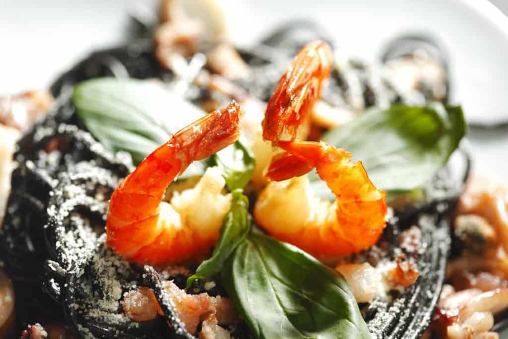 Squid ink spaghetti topped with succulent prawns and fresh basil leaves, served at Little Beach Boathouse, a top dining spot in Port Stephens. This visually striking dish showcases the restaurant's flair for unique seafood creations, making it a must-try for visitors seeking the best seafood dining experience in Port Stephens.