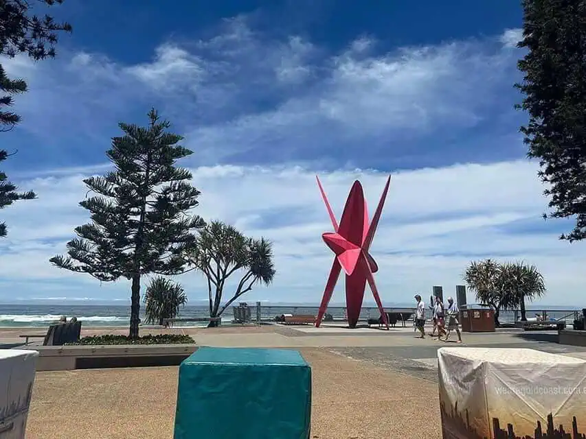 Surfers Paradise Beach viewed from the promenade, showcasing the iconic pink sculpture against a backdrop of the vibrant coastline, a staple in a Gold Coast itinerary.