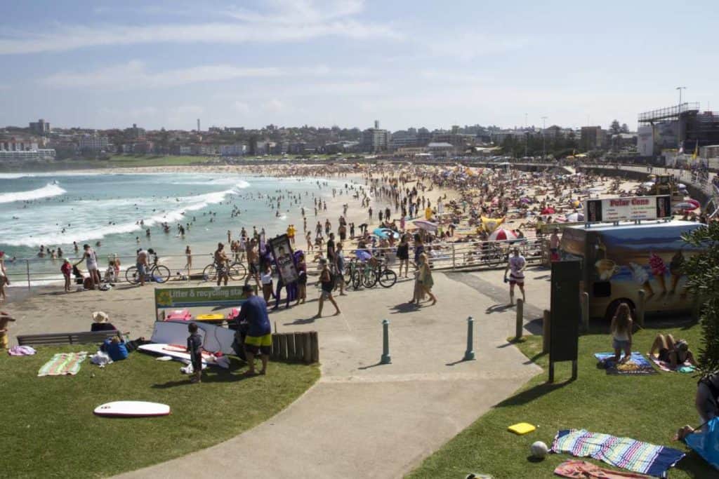 A crowded Bondi Beach in Sydney, Australia, taken in March, showing the bustling activity on the sand and promenade. This image highlights how busy Bondi Beach can get during this popular time.