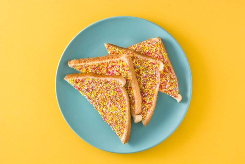 A plate of traditional Australian fairy bread, made with white bread, butter, and colourful sprinkles. This nostalgic and iconic Aussie treat is a favourite at children's birthday parties and celebrations.