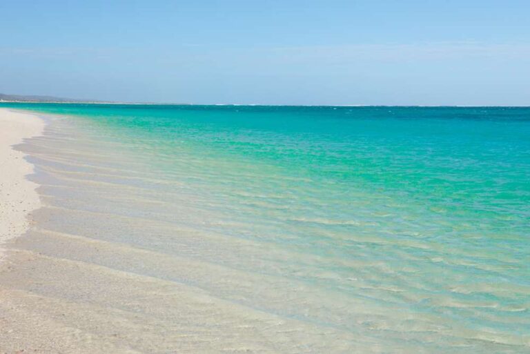 A serene view of Turquoise Bay with its clear, shallow waters and pristine sandy beach, epitomizing the untouched beauty of remote beaches in Australia.