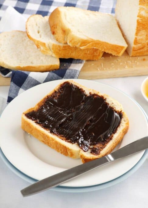 A slice of fresh white bread spread with Vegemite, a classic Australian food known for its rich, salty flavour. This iconic Aussie snack is a staple in households across Australia and is often enjoyed for breakfast or a quick bite.