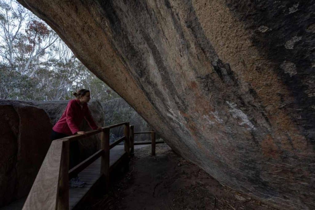 A visitor observing ancient Aboriginal rock art at Yankee Hat in Namadgi National Park, one of the hidden gems in ACT. This site features centuries-old Indigenous artwork, offering a glimpse into the region's rich cultural history. The peaceful bushland setting makes it a fascinating and secluded spot for nature lovers and history enthusiasts alike.